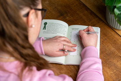 Person schreibt etwas in das Mitmachbuch Band 2 Hoppi Galoppi